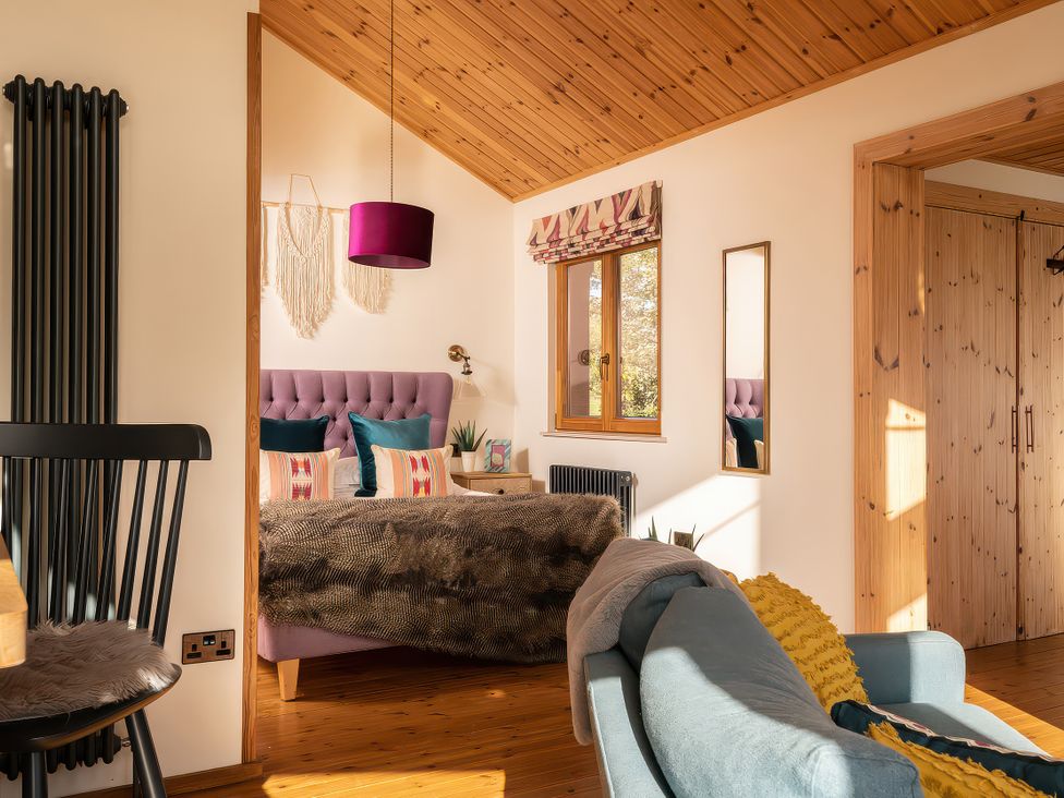 A bedroom with a bed and chair at Gezellig Log Cabin Llandrillo