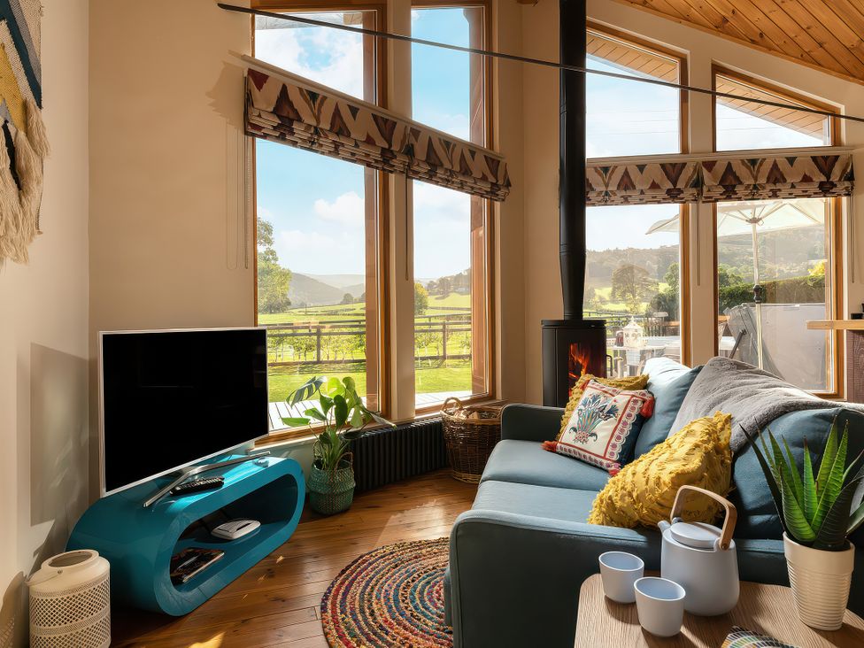 A living room with a sofa and television at Gezellig Log Cabin in Llandrillo