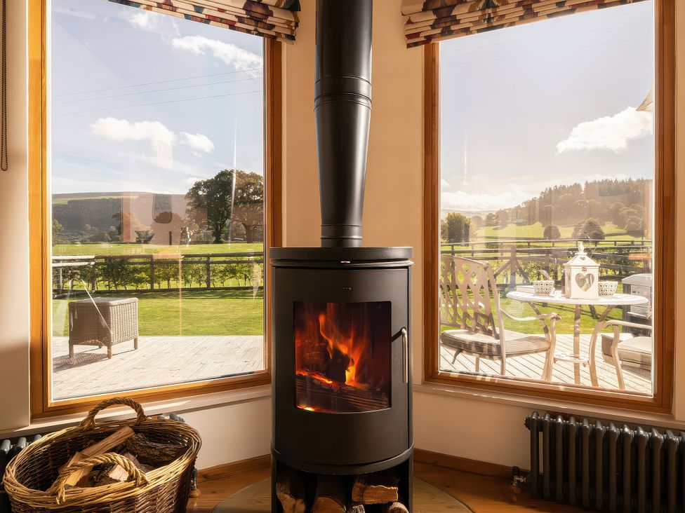 A living room with a stove and windows at Gezellig Log Cabin Llandrillo