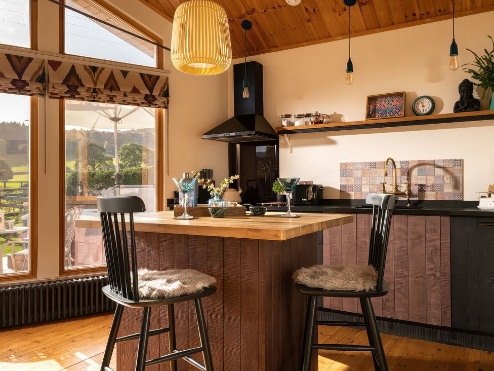 A kitchen with a counter and stools at Gezellig Log Cabin in Llandrillo