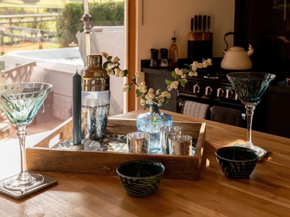 A kitchen countertop with a shaker, glasses, and a vase at Gezellig Log Cabin, Llandrillo