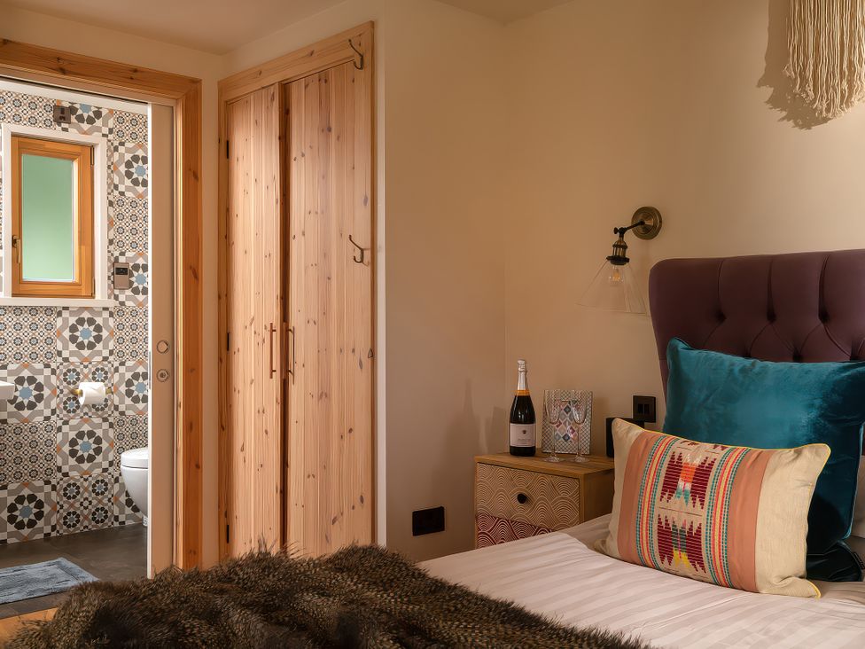 A bedroom with a bed and nightstand at Gezellig Log Cabin in Llandrillo