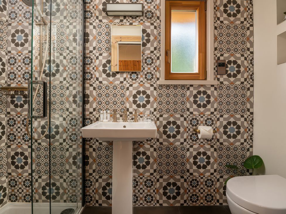 A bathroom with a shower, sink, mirror, and toilet at Gezellig Log Cabin in Llandrillo