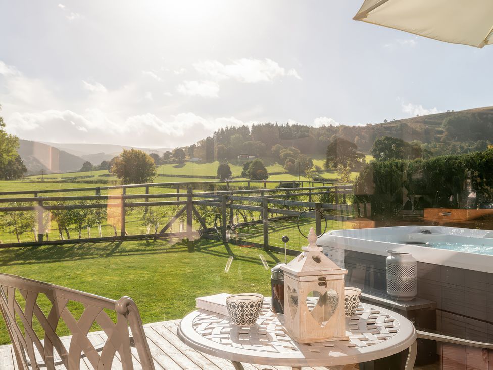 A table with cups and a lantern beside a hot tub at Gezellig Log Cabin in Llandrillo