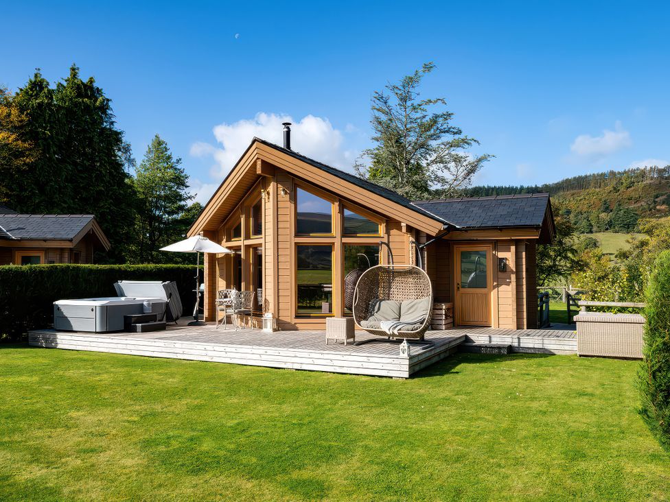 A wooden cabin with a deck and spa at Gezellig Log Cabin in Llandrillo