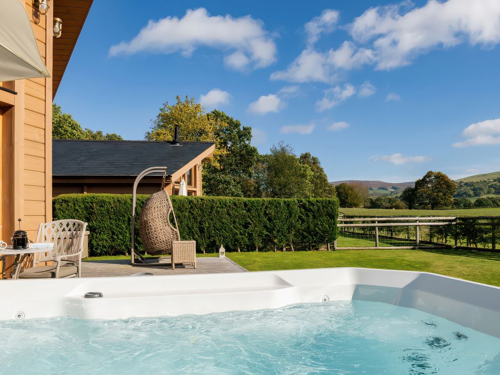 An outdoor area with a hot tub and wooden cabin at Gezellig Log Cabin Llandrillo