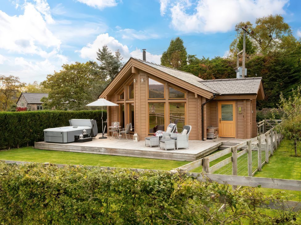 A log cabin with a deck and hot tub at Hyggelig Log Cabin in Llandrillo