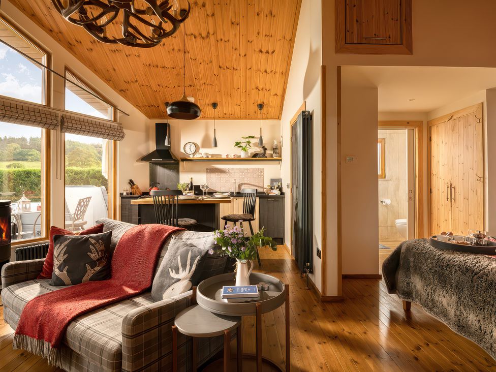 A living room with a sofa and kitchen in Hyggelig Log Cabin in Llandrillo