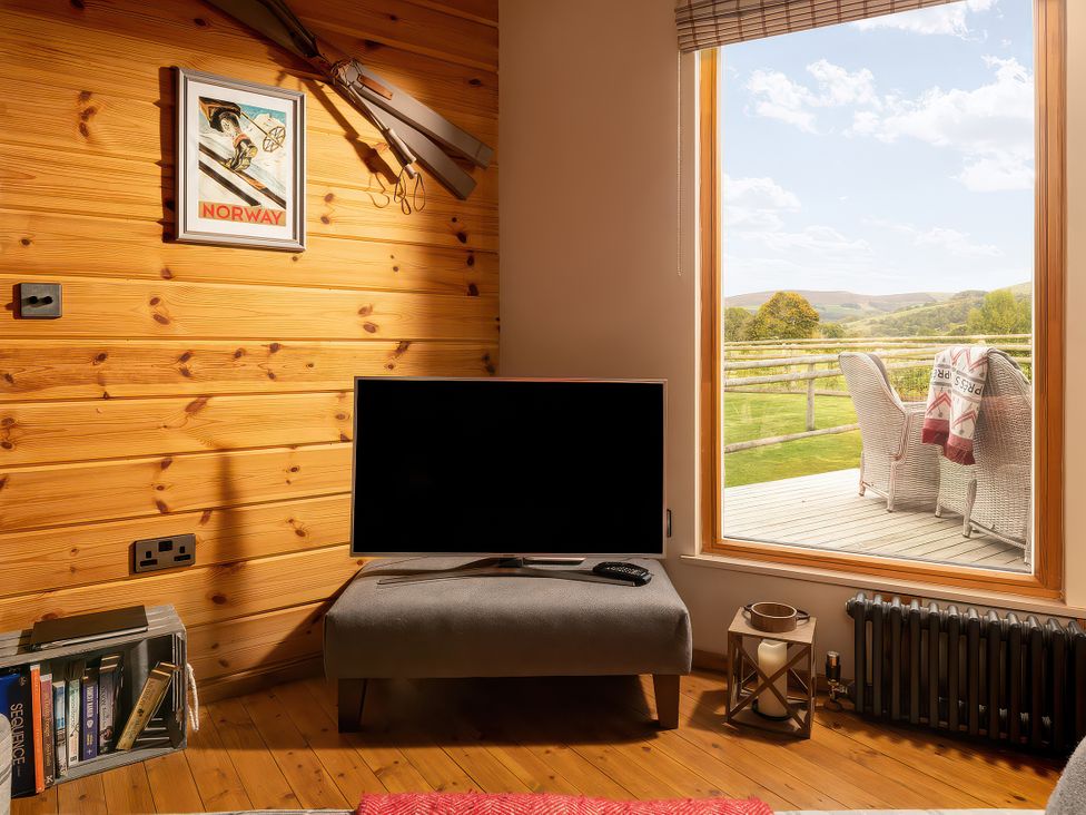 A living room with a television and window at Hyggelig Log Cabin Llandrillo