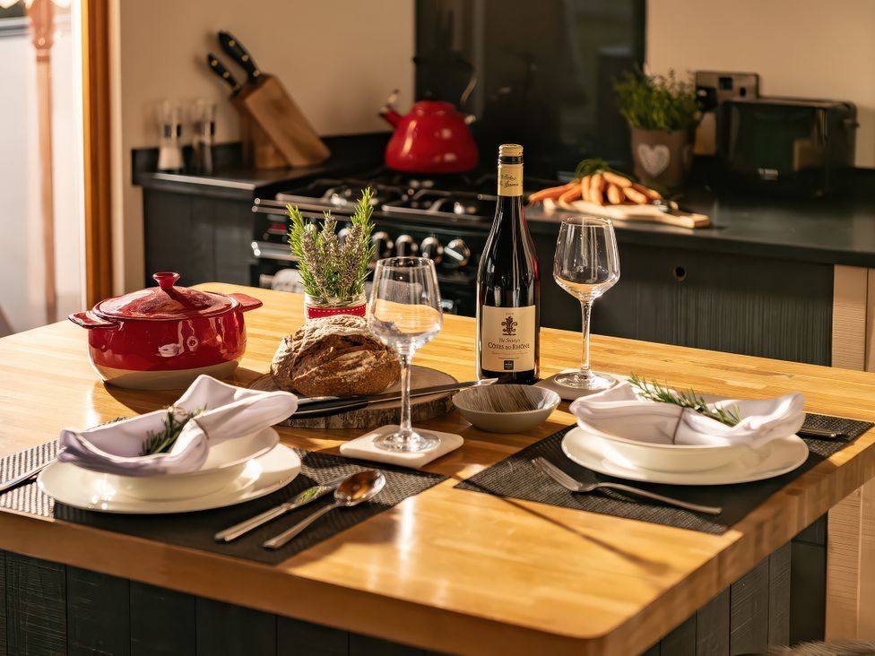 A kitchen with a dining table set for a meal at Hyggelig Log Cabin in Llandrillo