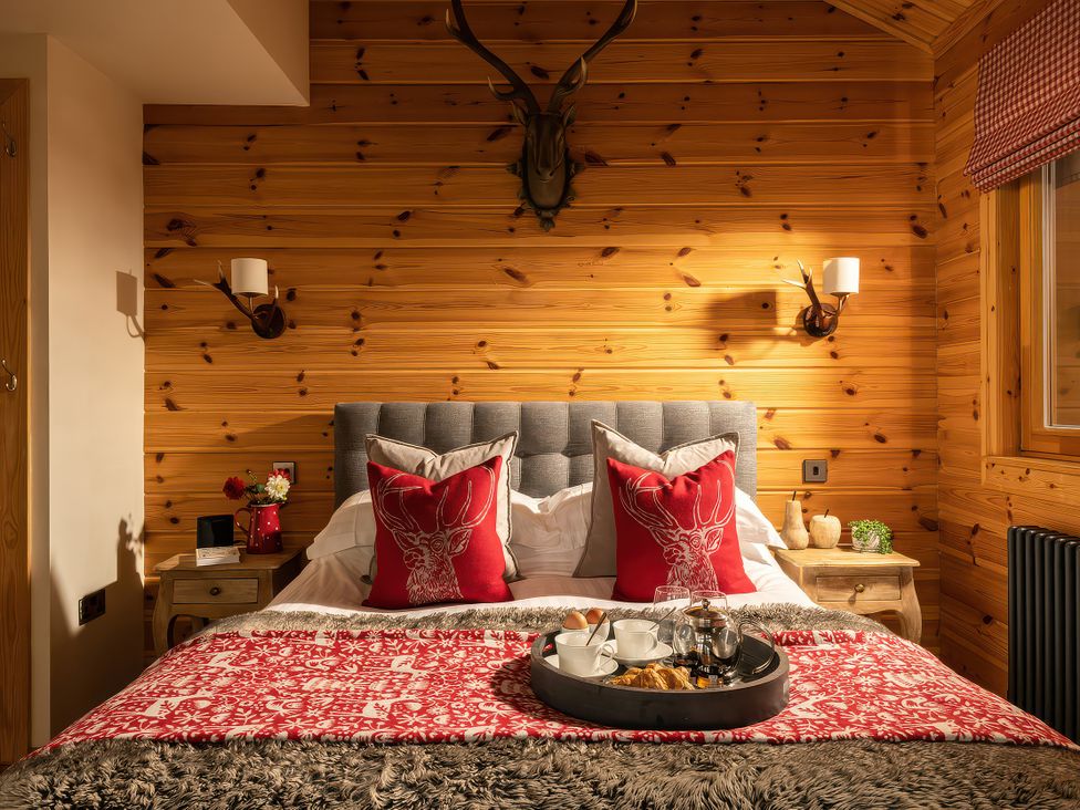 A bedroom with a bed, bedside table, and decorative items at Hyggelig Log Cabin in Llandrillo