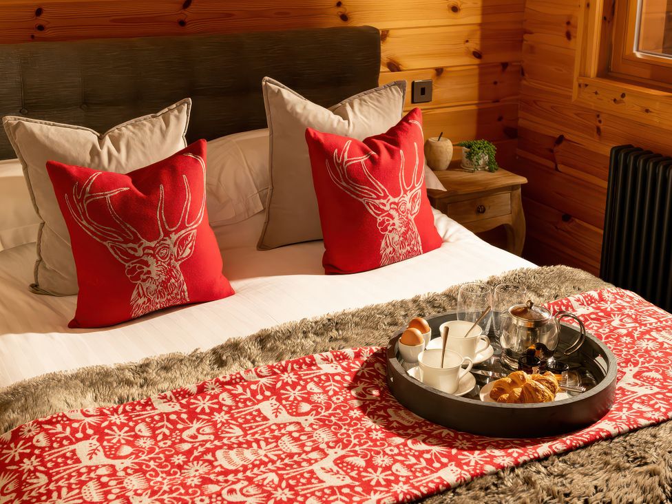 A bedroom with a tray of tea and snacks on a bed at Hyggelig Log Cabin Llandrillo