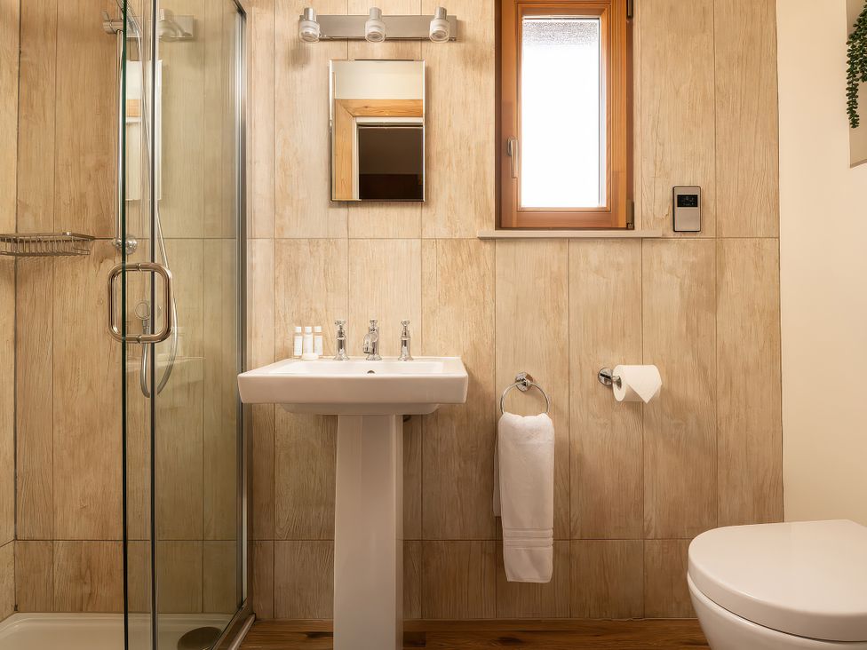 A bathroom with a shower, sink, and toilet at Hyggelig Log Cabin in Llandrillo