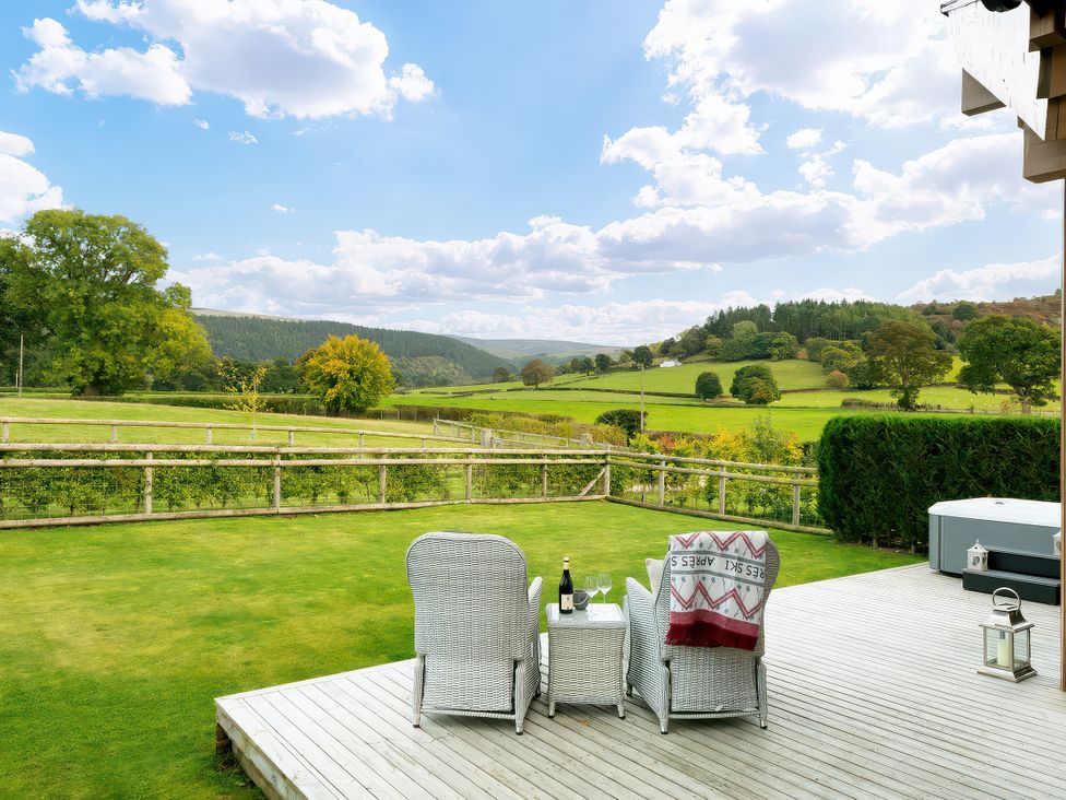 A garden with chairs and a table overlooking the countryside at Hyggelig Log Cabin Llandrillo
