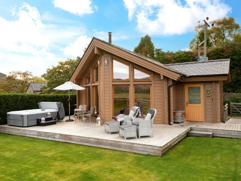 A hot tub and outdoor seating area at Hyggelig Log Cabin in Llandrillo