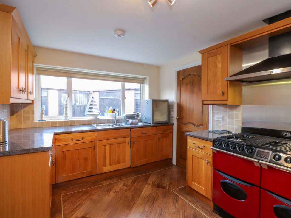 A kitchen with wooden cabinets and stainless steel stove at The Old Stables in Rhos-On-Sea