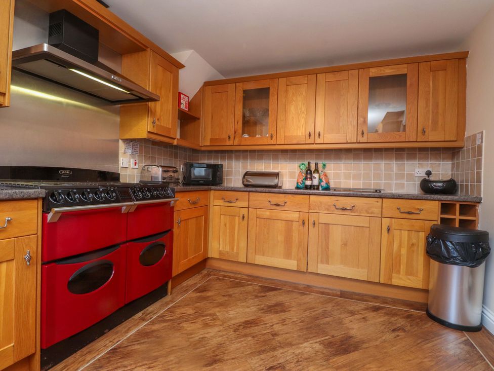 A kitchen with wooden cabinets and appliances at The Old Stables Rhos-On-Sea