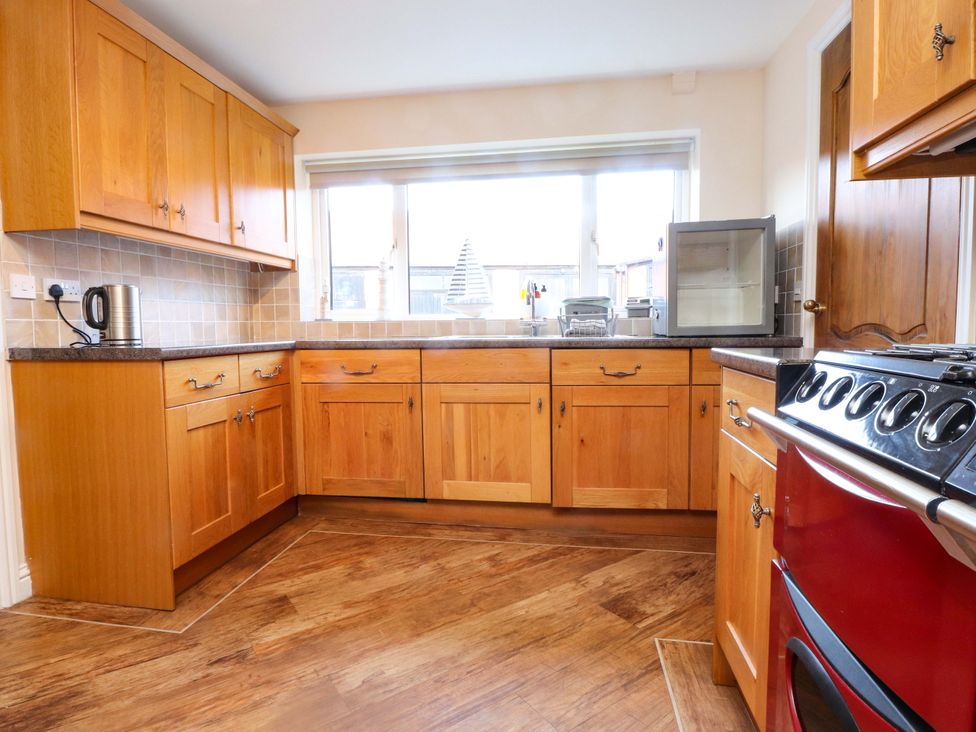 A kitchen with wooden cabinets and appliances at The Old Stables Rhos-On-Sea