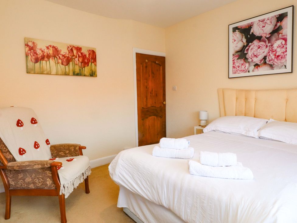 A bedroom with a bed, chair, and artwork at The Old Stables in Rhos-On-Sea