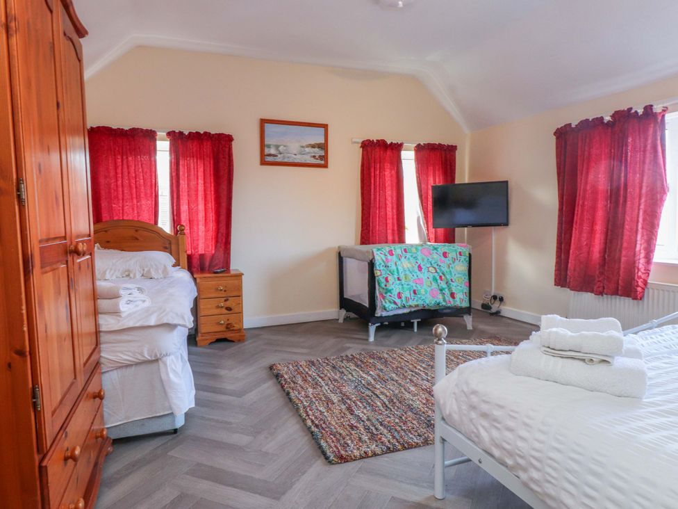 A bedroom with a bed and cot at The Old Stables in Rhos-On-Sea
