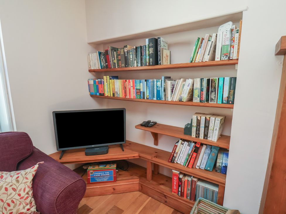 A living room with a bookshelf and a TV at Fleming Cottage