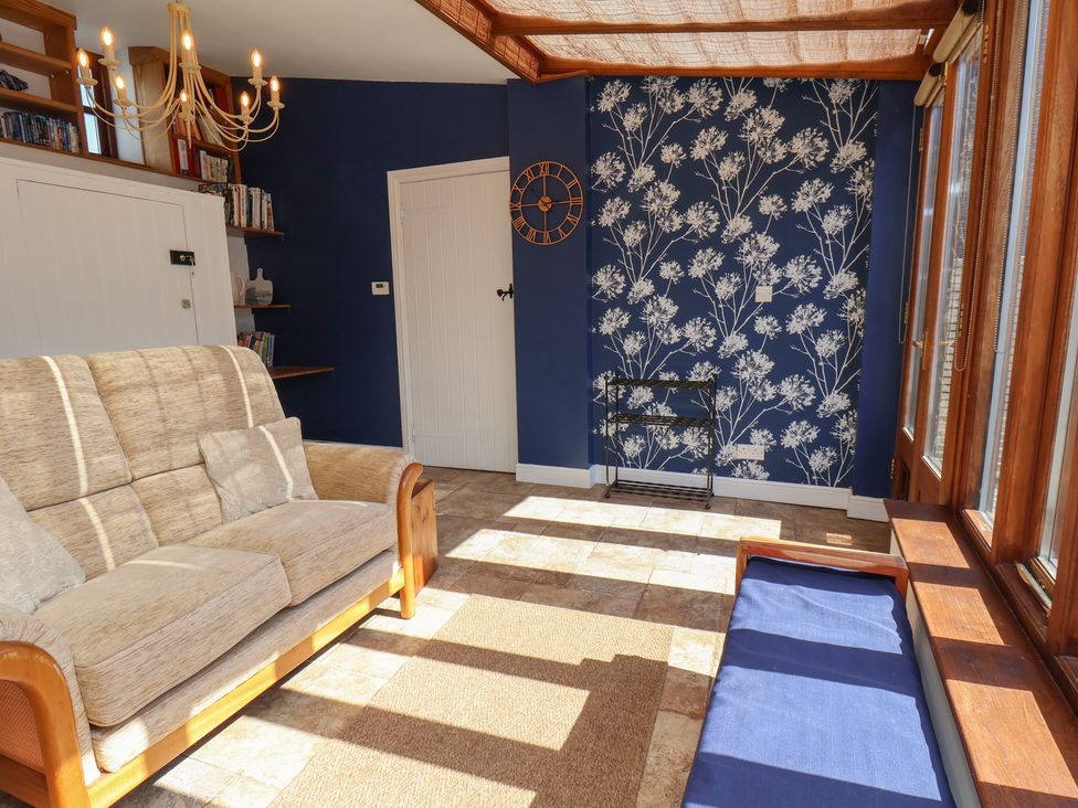 A snug with a sofa and a wall clock at Fleming Cottage