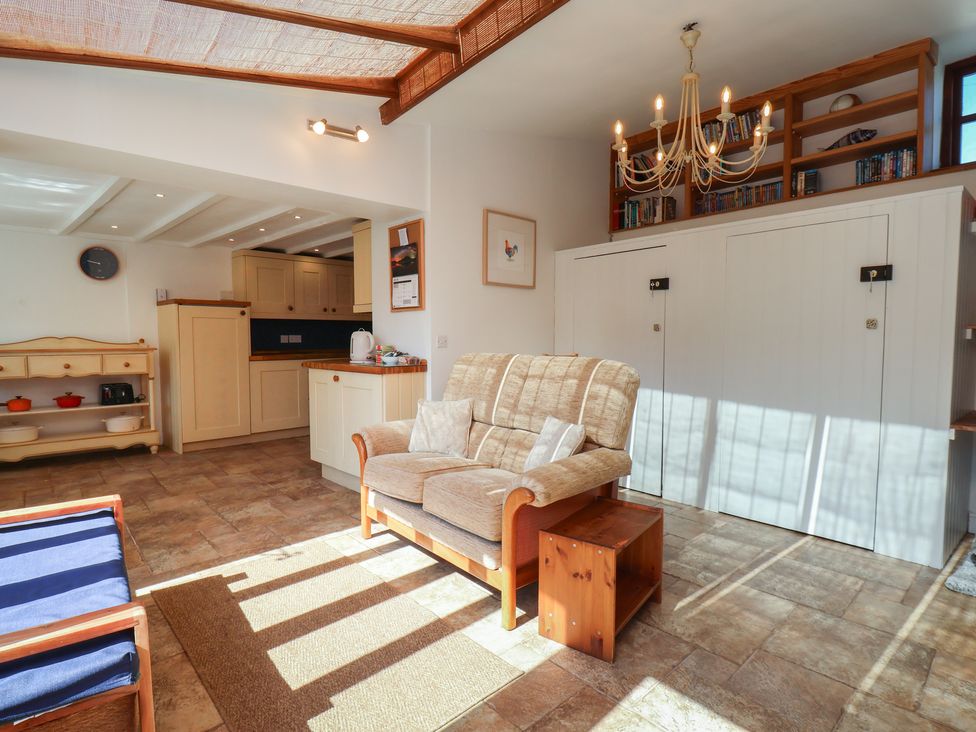 A living room with a sofa and kitchen area at Fleming Cottage
