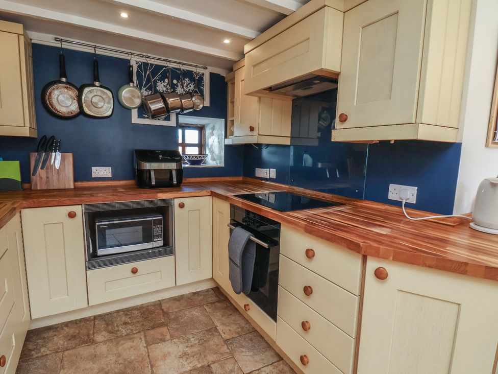 A kitchen with cabinets, countertop, microwave, and various cooking utensils at Fleming Cottage