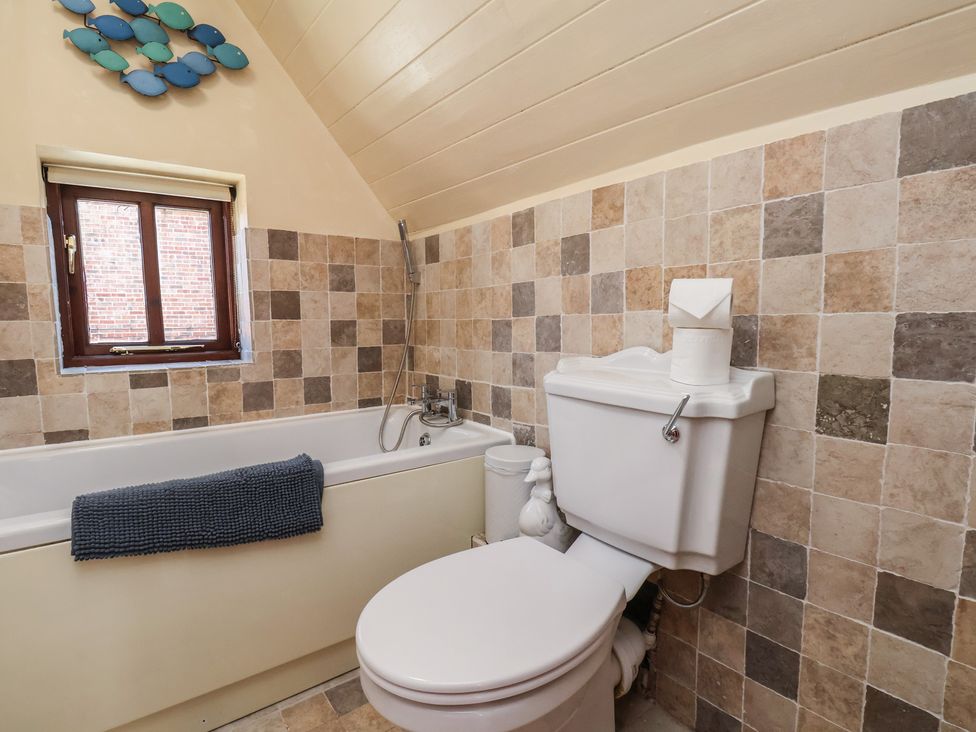 A bathroom with a bathtub and toilet at Fleming Cottage