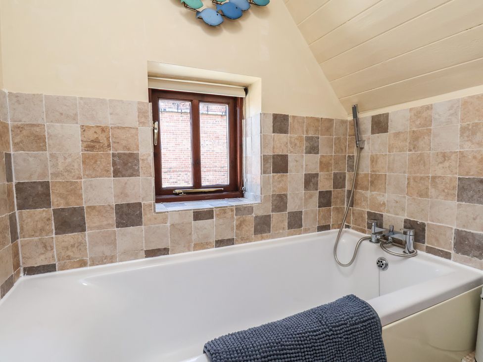 A bathroom with a bathtub and window at Fleming Cottage