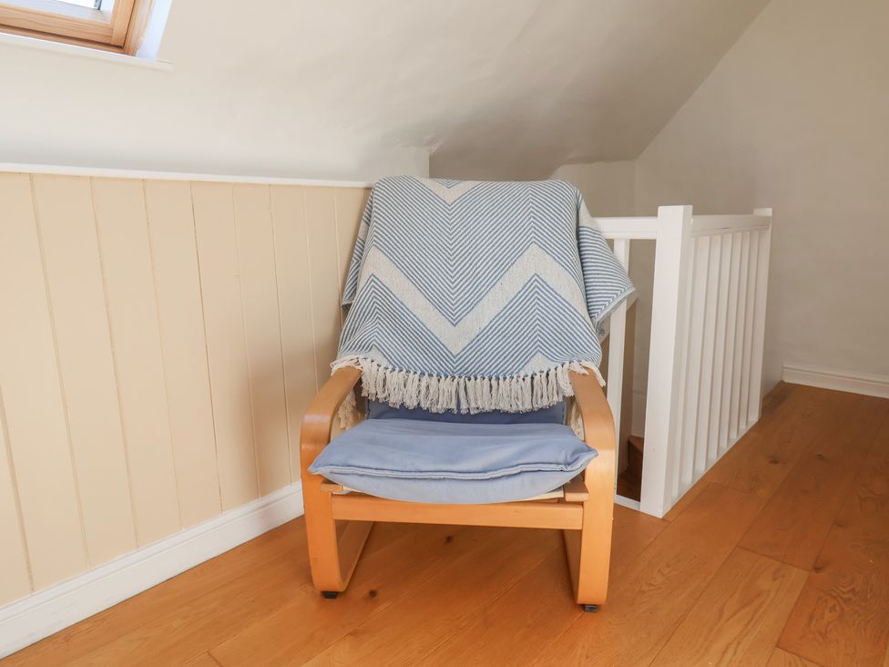 A chair with a blanket on it in a sitting area at Fleming Cottage
