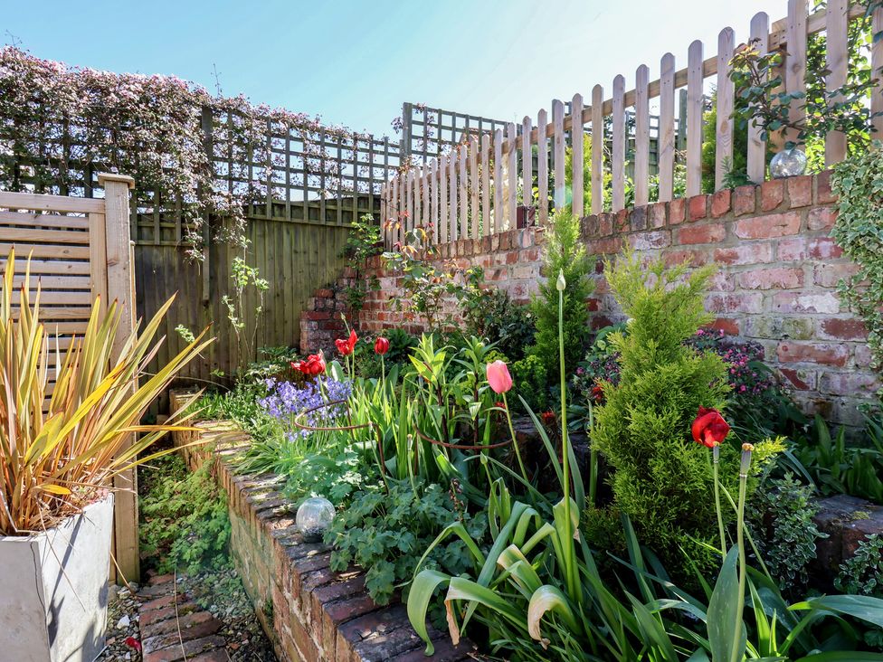A garden with flowers and a brick wall at Fleming Cottage 