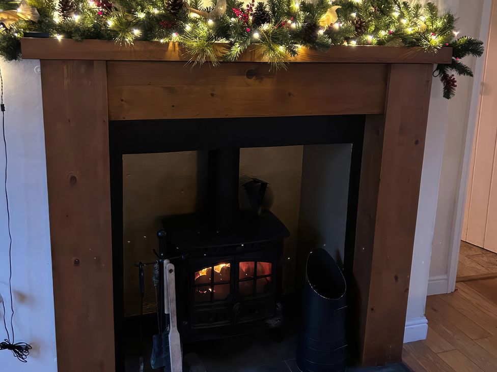 A fireplace with a wood stove and garland at Fleming Cottage in Hunmanby