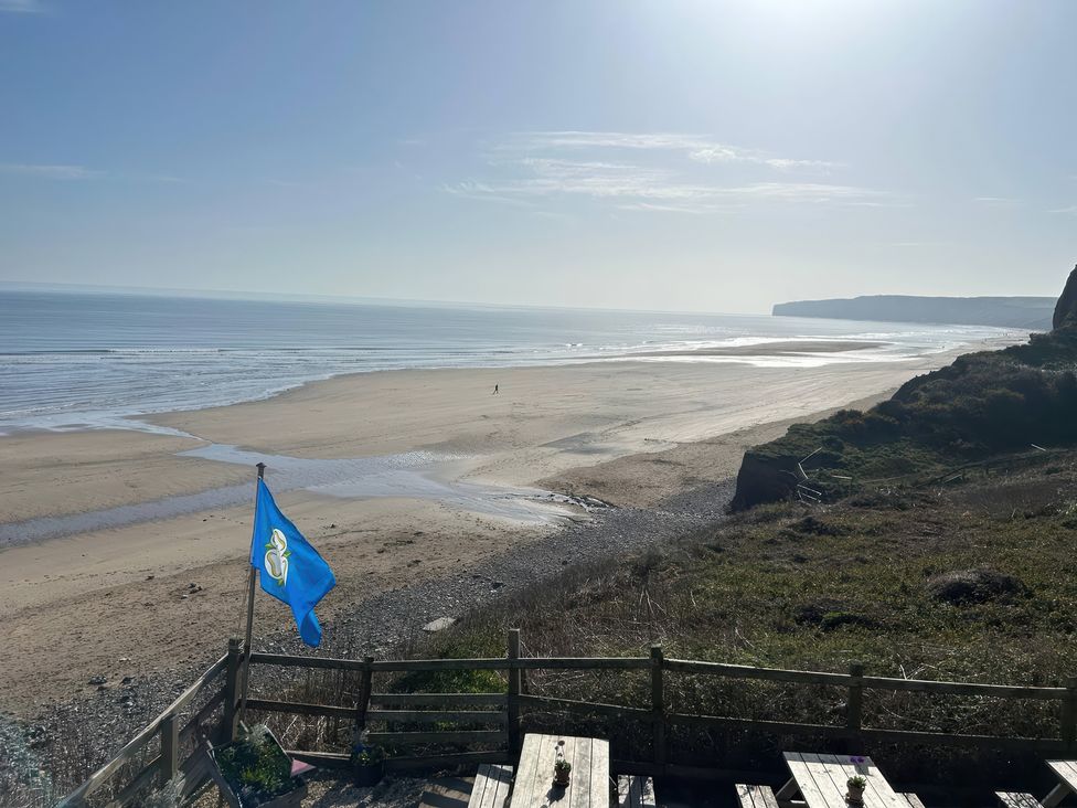 A beach with a flag and cliffs at Fleming Cottage in Hunmanby