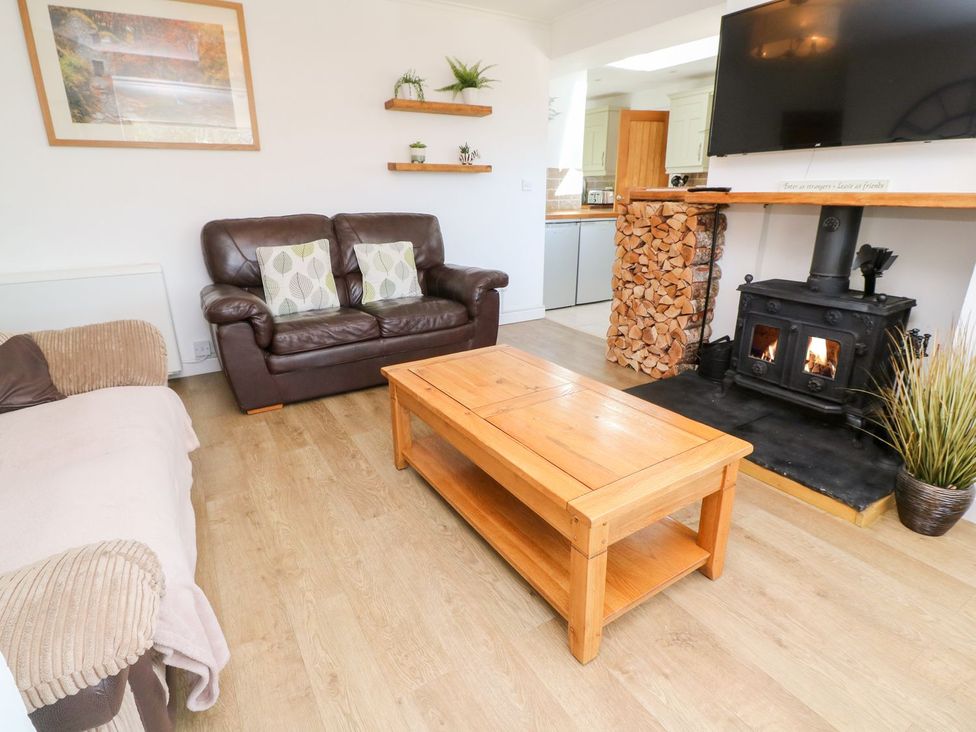 A living room with a sofa, coffee table, and wood stove at Tinners Way in Helston