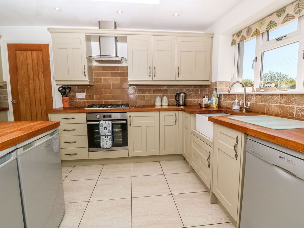 A kitchen with cabinets, cooker, sink, and refrigerator at Tinners Way in Helston