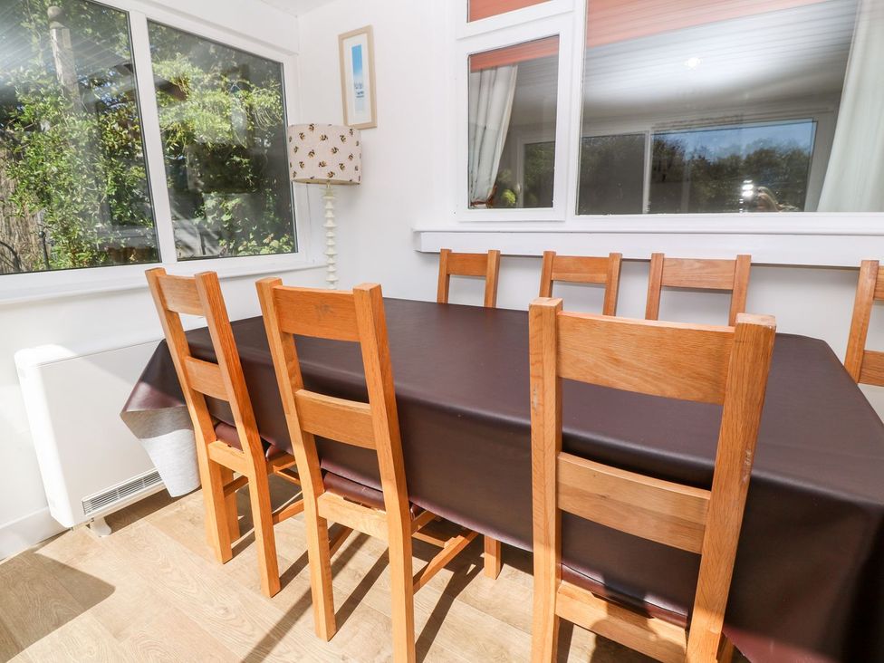 A dining table with chairs beside windows at Tinners Way in Helston
