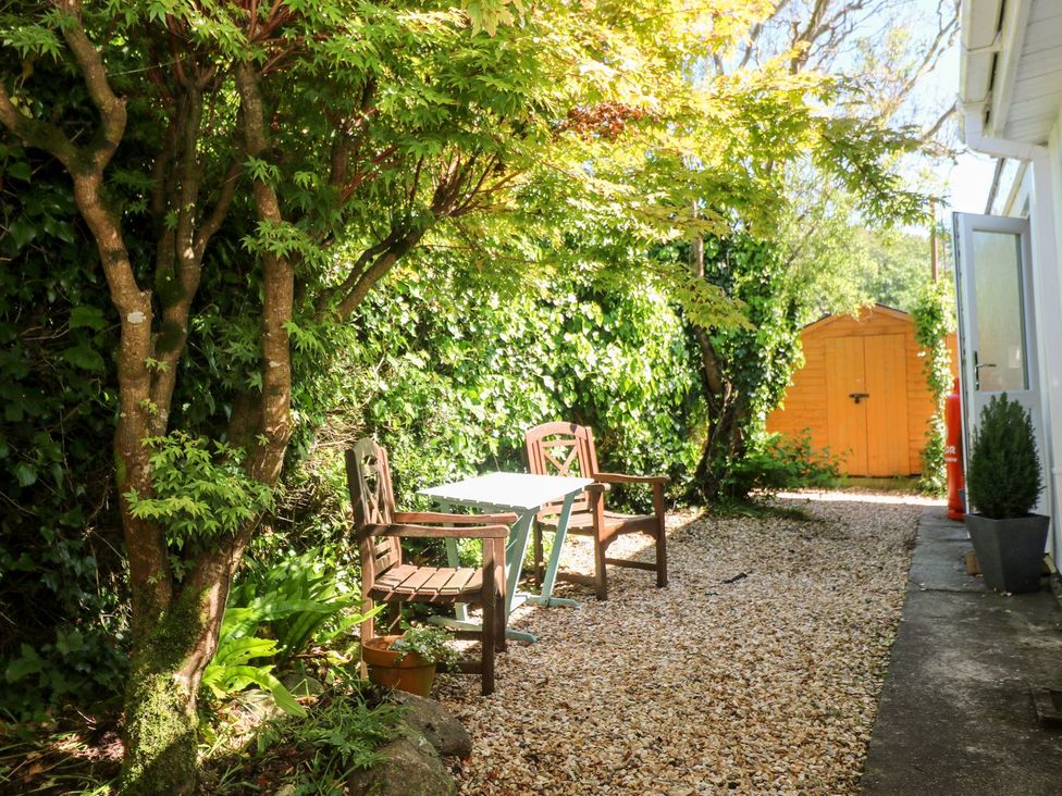 A garden with a table and chairs beside a yellow shed at Tinners Way Helston