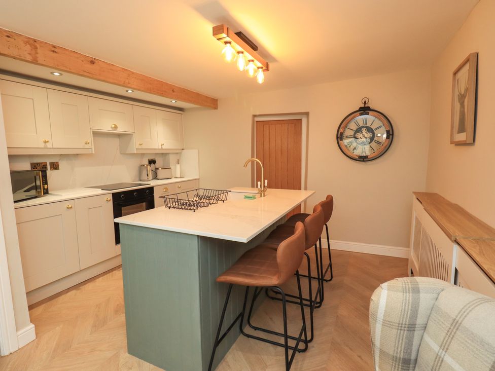 A kitchen with a countertop and stools at 7 Milnthorpe Road Holme near Burton-In-Kendal