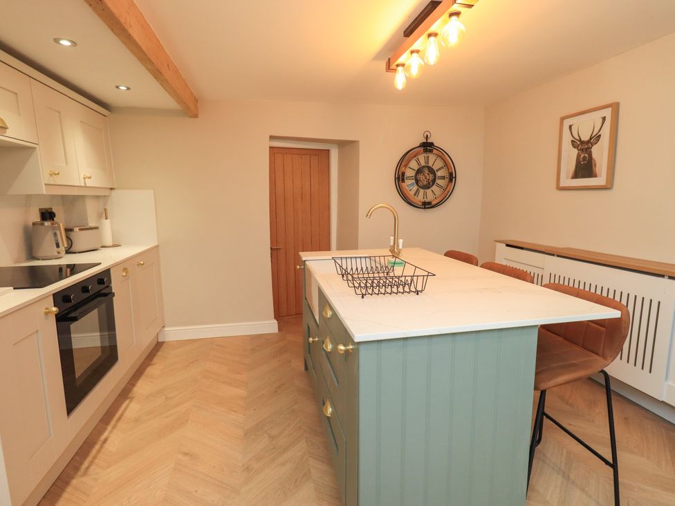 A kitchen with an island and stools at 7 Milnthorpe Road Holme near Burton-In-Kendal