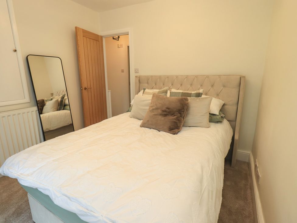 A bedroom with a bed and mirror at 7 Milnthorpe Road in Holme near Burton-In-Kendal