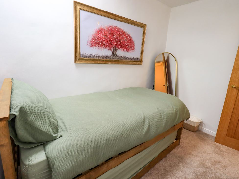 A bedroom with a bed and a mirror at 7 Milnthorpe Road Holme near Burton-In-Kendal