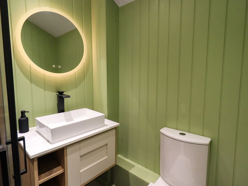 A bathroom featuring a sink, toilet, and mirror at 7 Milnthorpe Road Holme near Burton-In-Kendal