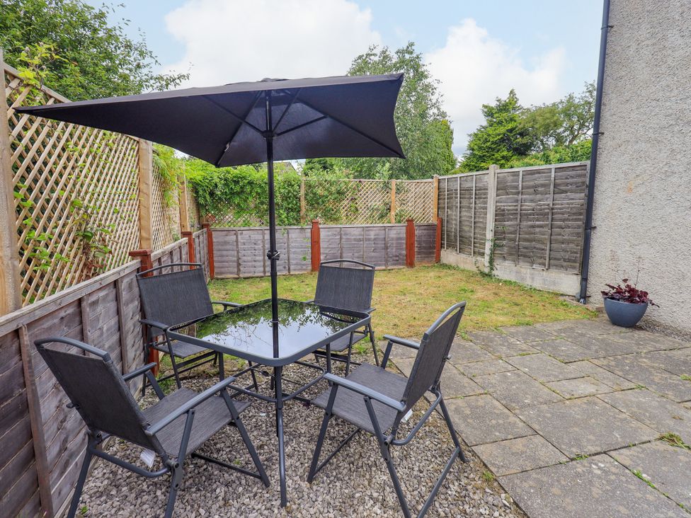 A garden with a table and chairs under an umbrella at 7 Milnthorpe Road Holme near Burton-In-Kendal