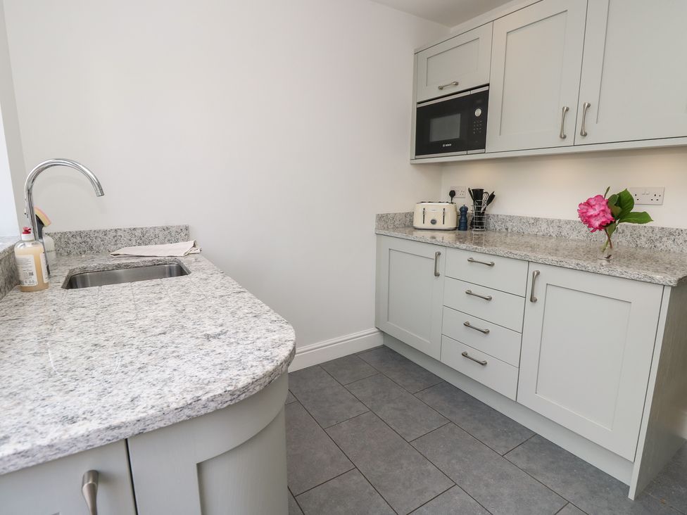 A kitchen with a sink and microwave at Cobblers Cottage in Lymington