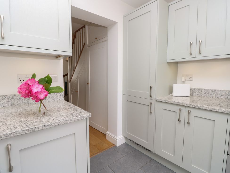 A kitchen with cabinets and a flower vase at Cobblers Cottage in Lymington
