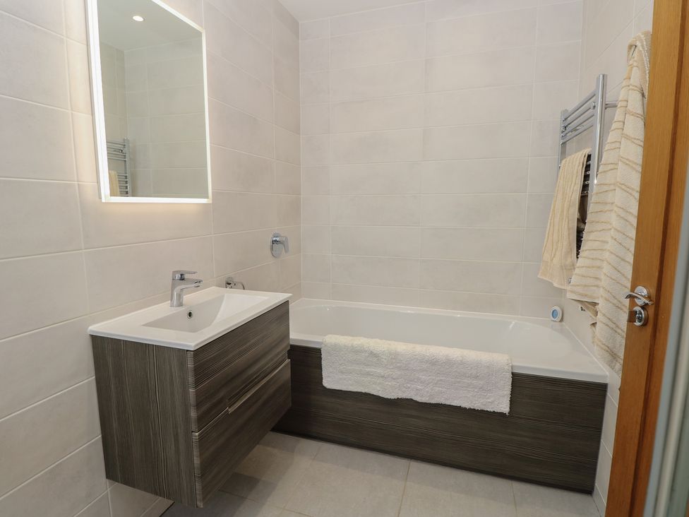 A bathroom with a bath tub and sink at Cobblers Cottage in Lymington