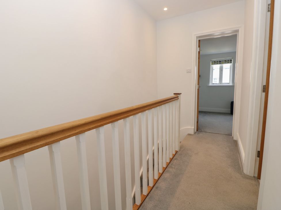 A hallway with a handrail and doorways at Cobblers Cottage in Lymington