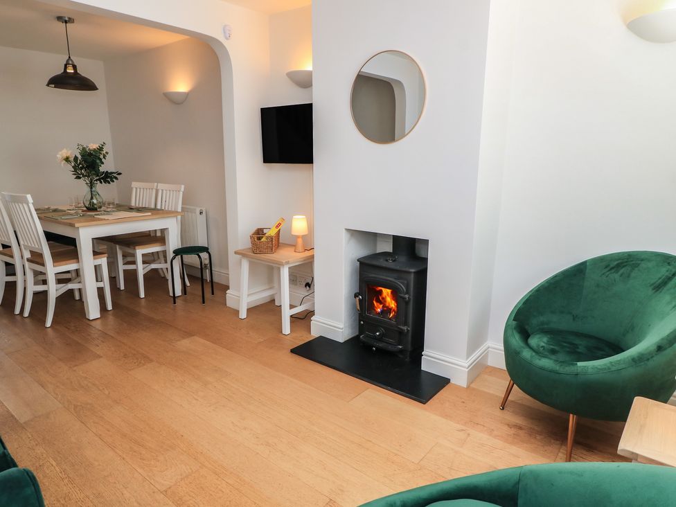 A living room with a fireplace and dining area at Cobblers Cottage in Lymington