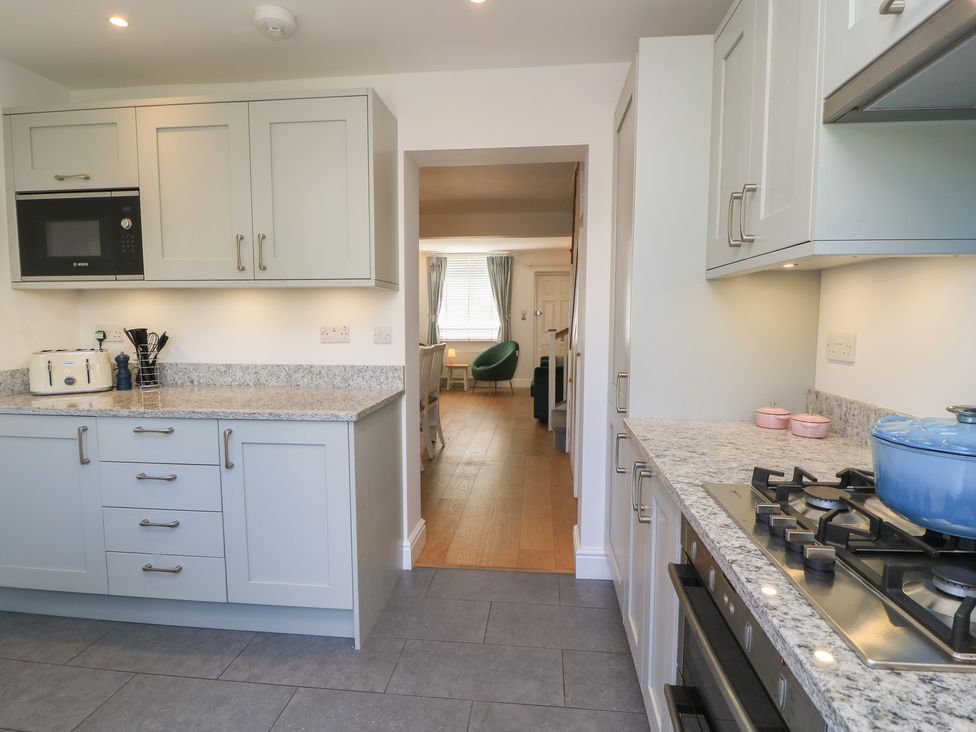 A kitchen with appliances and a view into the living area at Cobblers Cottage in Lymington